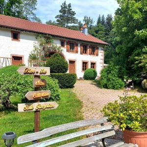 Un cartel de madera delante de una casa con un banco. en La Grande Ferme, en La Chapelle