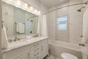 a white bathroom with a tub and a sink and a mirror at 2 Bedroom Near Trolley Square and Liberty Park! in Salt Lake City