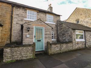 an old stone house with a blue door at Buttercup Cottage in Bakewell
