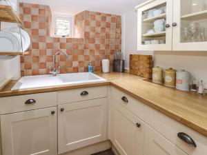 a kitchen with white cabinets and a sink at Buttercup Cottage in Bakewell +13 photos