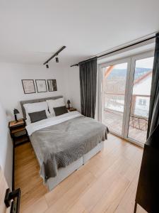 1 dormitorio con cama y ventana grande en Apartamenty Larice - basen, sauna i balia en Świeradów-Zdrój