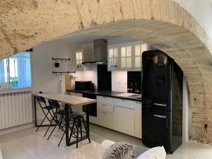a kitchen with a black refrigerator and a table at L'Appartement de La Mouline in Pézenas