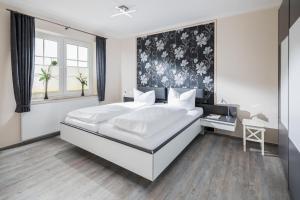 1 dormitorio con 1 cama blanca grande y cabecero de flores en Albatros en Norderney