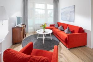 een woonkamer met een rode bank en een tafel bij Alte Teestube 53 in Norderney