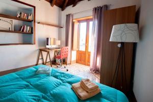 um quarto com uma cama azul, um candeeiro e uma secretária. em Casa degli Ospiti em Alimena