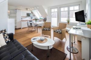 een woonkamer en een keuken met een bank en een tafel bij FeWo am Park in Norderney