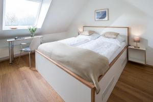 een slaapkamer met een groot bed, een bureau en een raam bij FeWo am Park in Norderney