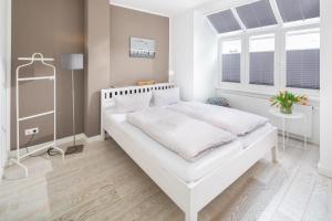 a bedroom with a large white bed with white sheets at Haus Kapitänshaus Seilerstrasse in Norderney