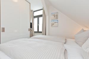 een witte slaapkamer met een bed en een raam bij Jann 66 in Norderney