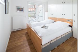 two beds in a room with white walls and wood floors at John Silver in Norderney
