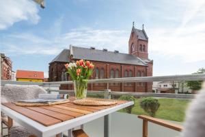 a table with flowers on a balcony with a church at John Silver in Norderney
