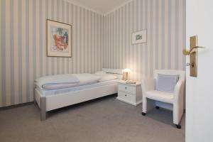 1 dormitorio con 1 cama y 1 silla blanca en Lenz, en Norderney