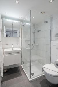 uma casa de banho com um chuveiro, um lavatório e um WC. em Kaiserhof 76 em Norderney