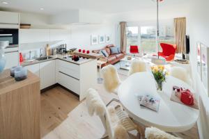 uma cozinha e sala de estar com uma mesa branca e cadeiras em Neys Beach Loft em Norderney