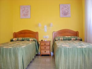 Hostal Santa Marta Playa في بايونا: سريرين في غرفة بجدران صفراء