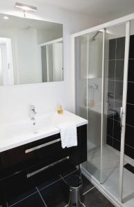 La salle de bains est pourvue d'un lavabo et d'une douche. dans l'établissement Ténéo Apparthotel Talence Arthena, à Talence