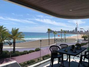 een balkon met een tafel en stoelen en het strand bij Apartamento de lujo en primera linea de playa in Benidorm