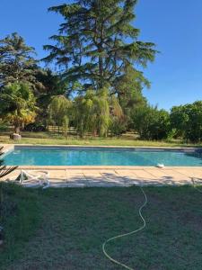 a swimming pool with a hose laying on the grass at Gîte cocooning avec piscine in Bougé-Chambalud