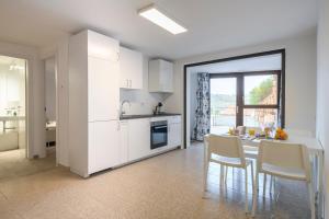 uma cozinha com armários brancos e uma mesa com cadeiras em Cosy and Modern Apartment Portu Frailis em Àrbatax