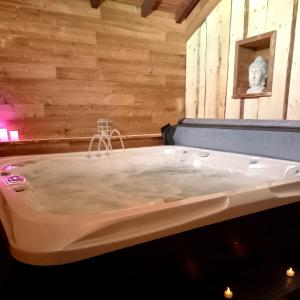 a bath tub in a room with wooden walls at La petite ferme in La Chapelle