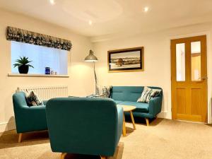 a living room with two blue chairs and a table at 8 Standard Street by The Bear Hotel Crickhowell in Crickhowell
