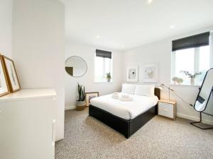 a white bedroom with a bed and a mirror at Amazing and 3 bedroom house in Deptford in London