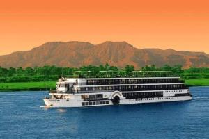 a cruise ship on the water with mountains in the background at Nile Roof Hotel& Restaurant in Luxor