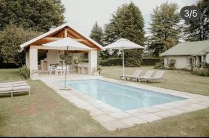 a swimming pool with two umbrellas and a house at Elgin Guest House in Underberg