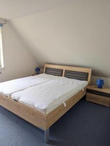 - une chambre avec un lit en bois et 2 tables de chevet dans l'établissement Karl Sonnenstrahl, à Wulfen auf Fehmarn