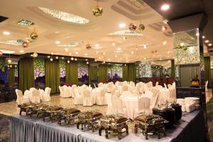 a banquet hall with white tables and chairs and chandeliers at Humming Bird Hotel & Banquet in Anand