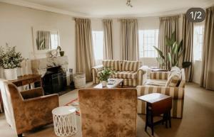 a living room with couches chairs and a fireplace at Elgin Guest House in Underberg