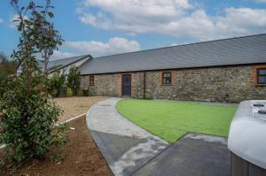 a stone building with a lawn in front of it at The Barn At Kiln Park - 2 Bed Cottage - Narberth in Narberth