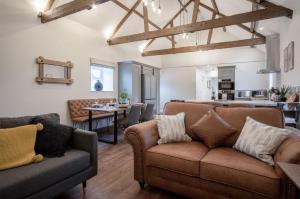 a living room with two couches and a kitchen at The Barn At Kiln Park - 2 Bed Cottage - Narberth in Narberth