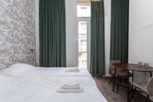1 dormitorio con cama, mesa y cortinas verdes en Studio Anvers, en Amberes