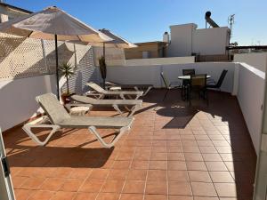 a patio with chairs and tables and an umbrella on a roof at Apartamentos Jimmy 2 in Nerja