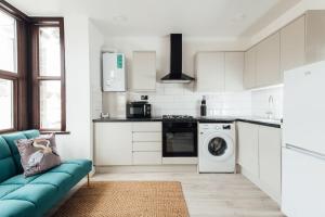 a kitchen with a blue couch and a washing machine at Modern 2 Bedroom Flat in Ilford, London in Ilford