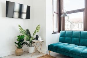 a blue couch in a living room with plants at Modern 2 Bedroom Flat in Ilford, London in Ilford