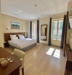 um quarto com uma cama e uma mesa num quarto em Hôtel La Falaise em Cotignac