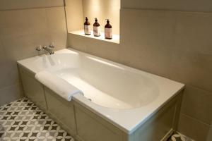 a white bath tub in a bathroom with two bottles at Portree, Isle of Skye in Portree