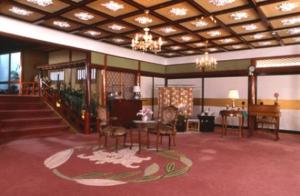 下田市にあるクアハウス石橋旅館の椅子とテーブル、階段が備わる広い客室です。