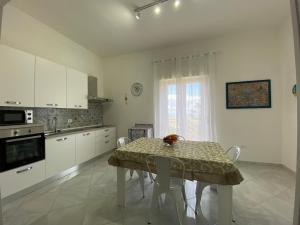 eine Küche mit einem Tisch und Stühlen sowie eine Küche mit weißen Schränken in der Unterkunft Perla Diva Apartment in Palermo