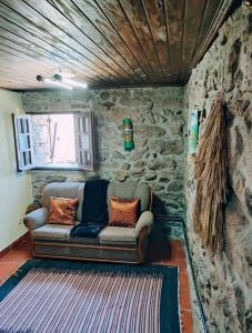 un sofá sentado en una habitación con una pared de piedra en Casa da Fonte - Branda da Aveleira, en Melgaço