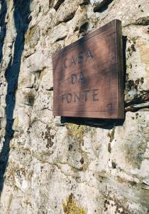 una señal de madera en un lateral de una pared de piedra en Casa da Fonte - Branda da Aveleira, en Melgaço