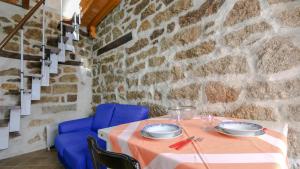 a table with blue chairs and a stone wall at Welcomely - Sa Dommedda in Nuoro