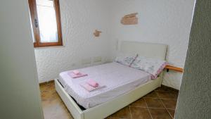 a small bedroom with a small bed with two pink towels at Welcomely - Sa Dommedda in Nuoro