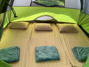 a large bed in a green tent with two pillows at The Triple M Mountain Resort in Ban Muang Ton Mamuang