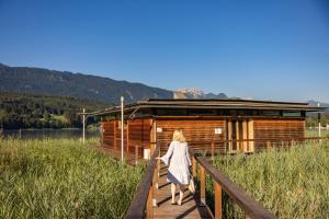 Una donna che cammina lungo un ponte di legno verso una cabina. di Lake Resort Pressegger See a Hermagor