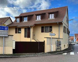 uma casa amarela com um telhado castanho numa rua em Sur la route des vins entre Colmar et Strasbourg em Scherwiller