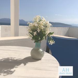 un vase avec des fleurs blanches assises sur une table dans l'établissement Hotel Areti, à Égine