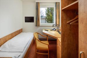 Kleines Zimmer mit einem Bett, einem Schreibtisch und einem Fenster in der Unterkunft Academy Lodge Boardinghouse in Hamburg
